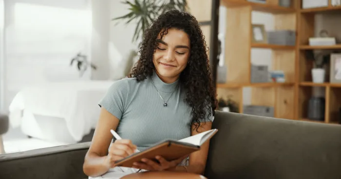 student sitting on couch and writing notes